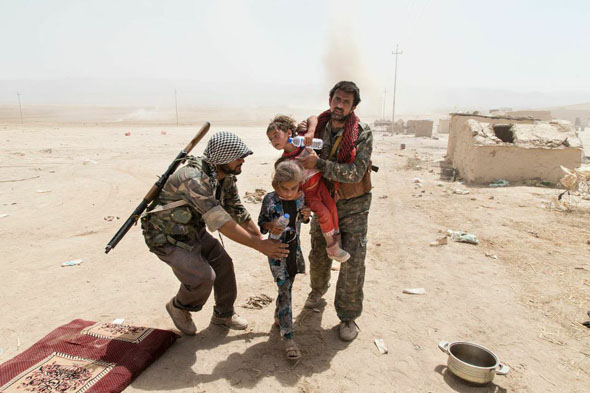 دو مبارز کرد سوریه به دو کدوک ایزدی در فاصله میان مرز سوریه و عراق کمک می‌کنند. Zmnako Ismael/Metrography 